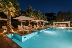 a pool with chairs and umbrellas at night at Resort Miramonti in Forte dei Marmi