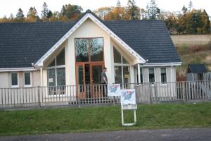 un homme debout devant une maison dans l'établissement BCC Loch Ness Hostel, à Bearnock