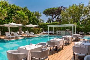 a poolside restaurant with tables and chairs next to a pool at Resort Miramonti in Forte dei Marmi