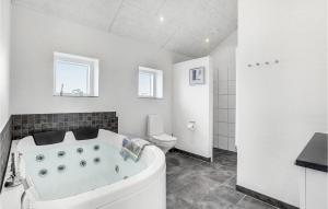 a white bathroom with a tub and a toilet at Holiday Home Fyrvej Blåvand Iv in Blåvand +31 photos