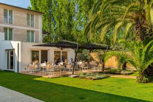 a patio with tables and umbrellas in front of a building at Resort Miramonti in Forte dei Marmi