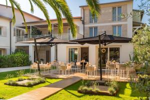 a patio with tables and umbrellas in front of a building at Resort Miramonti in Forte dei Marmi