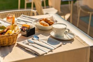 a table with a cup of coffee and a basket of pastries at Resort Miramonti in Forte dei Marmi