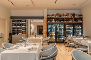 a restaurant with white tables and chairs and shelves of wine bottles at Resort Miramonti in Forte dei Marmi