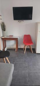 a living room with a red chair and a tv at Tsampikas House in Faliraki