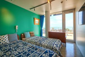 two beds in a room with a green wall at zaimokuza seasons in Kamakura