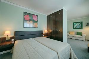a bedroom with a large bed and a couch at Hotel Apartamento Solverde in Espinho