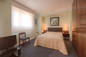 a bedroom with a bed and a flat screen tv at Hotel Apartamento Solverde in Espinho