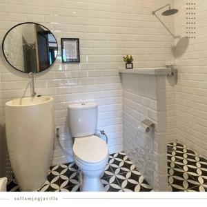a bathroom with a white toilet and a mirror at Villa The Noman Tawangmangu by Suasana Villa in Sarangan