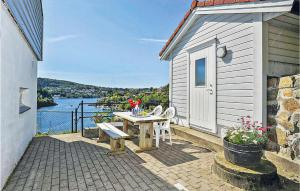 a table and bench on a patio with a view of the water at Cozy Apartment In Straumsgrend in Bergen