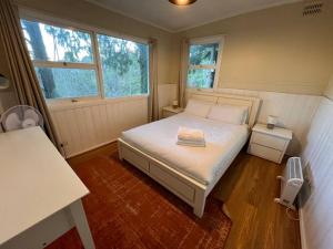 ein kleines Schlafzimmer mit einem Bett und zwei Fenstern in der Unterkunft Pine Hill Cottage - shabby chic & peaceful haven in Katoomba