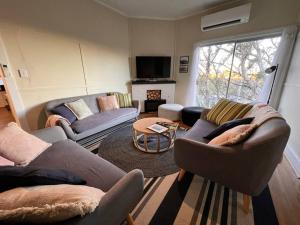 ein Wohnzimmer mit zwei Sofas und einem Kamin in der Unterkunft Pine Hill Cottage - shabby chic & peaceful haven in Katoomba