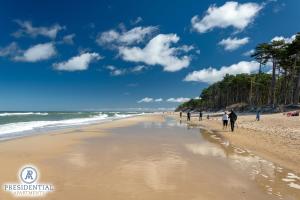 a group of people walking on the beach at Baltic Houses domki apartamentowe nad morzem przy plaży in Kopań