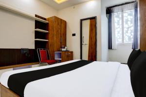 a bedroom with a white bed and a red chair at HOTEL O ANUSHTHAN in Jabalpur