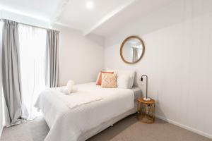 a white bedroom with a white bed and a mirror at The Cottage- Pet friendly, Golf, Ocean and River! in Ocean Grove
