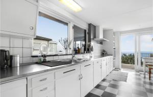 a kitchen with white cabinets and a large window at Beautiful Home In Gudhjem in Gudhjem +18 photos