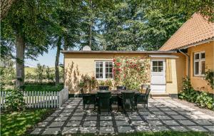 a patio with a table and chairs in front of a house at Risegård, Lejl B in Åkirkeby