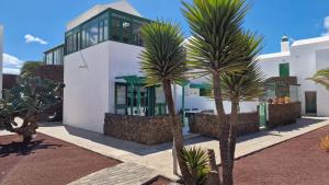 a white house with palm trees in front of it at La Islita in Playa Blanca