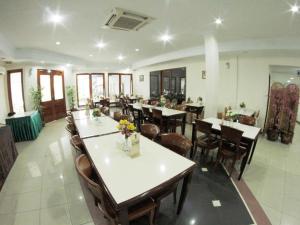 uma sala de jantar com mesas e cadeiras em um restaurante em Puri Mega Hotel em Jacarta
