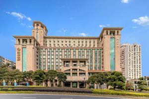 a large building with trees in front of it at Yihe Grand Hotel in Zhongshan