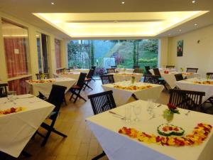 a dining room with white tables and chairs at Casa Monte Rosa in Puncak