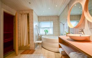 ein Badezimmer mit Badewanne, Waschbecken und Spiegel in der Unterkunft Holiday Home Ebeltoft V in Ebeltoft