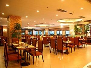 uma sala de jantar com mesas e cadeiras em um restaurante em Qingdao Blue Horizon Hotel Laoshan em Qingdao