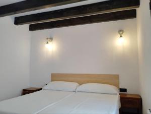 a bedroom with a white bed and two lights on the wall at La BUHARDILLA DE CHARLIN in Casas de Ves