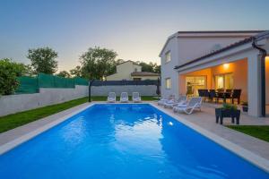 a swimming pool with chairs and a house at Villa Putina by IstriaLux in Svetvinčenat