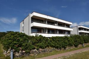a white building with bushes in front of it at Haus Calma App 7 in Wenningstedt