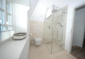 ein Badezimmer mit Glasdusche und WC in der Unterkunft Landhaus Strandhafer HT 1 in Wenningstedt-Braderup + 12 Fotos