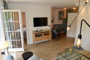 a living room with a television and a desk with a table at Westerhuk App 3 in Keitum