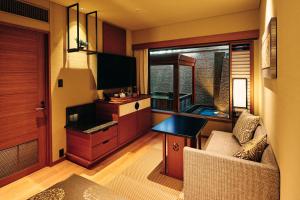 a living room with a couch and a desk and a window at Sora Niwa Terrace Kyoto Bettei in Kyoto