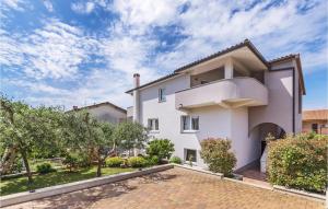 a white house with a courtyard and trees at 2 Bedroom Cozy Apartment In Pula in Veli Vrh