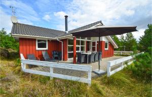 una casa rossa con tavolo e ombrellone di Holiday Home Jtagholmsvej Rømø X a Rømø Kirkeby