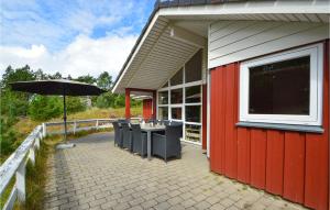 un edificio rosso con tavolo e ombrellone di Holiday Home Jtagholmsvej Rømø X a Rømø Kirkeby