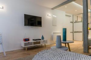 a living room with a tv on a white wall at Grand studio Colmar Centre in Colmar