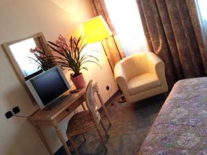 Habitación con escritorio, TV y silla. en Hotel Ca' Brugnera en Brugnera