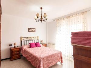 a bedroom with a bed with pink sheets and a chandelier at Casa La Palmera in Dúrcal +32 photos