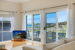 a living room with sliding glass doors with a view of the ocean at 8 Sunnyside Crescent Kianga in Kianga