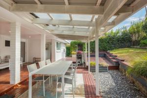 a patio with a table and chairs under a pergola at 8 Sunnyside Crescent Kianga in Kianga