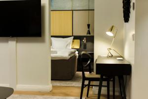 a bedroom with a bed and a desk with a chair at Quality Hotel Sveitsi in Hyvink&auml;&auml;