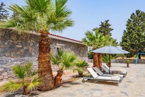 a group of chairs and an umbrella and palm trees at Madia Villa in Kolimbia
