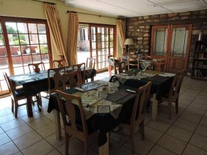 un comedor con mesas, sillas y ventanas en Savanna Guest Farm, en Grünau