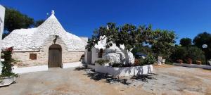 a white church with a tree in a yard at Trullo Antelmi in Ceglie Messapica