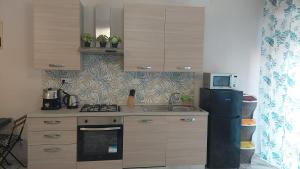 a kitchen with a refrigerator and a sink and a microwave at Appartamento centrale in Lido di Ostia