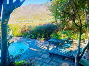 a patio with two benches and a swimming pool at Sunset Haven Ocean, Mountain & Valley Views in Cape Town