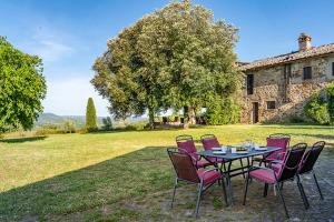 a table with pink chairs sitting in front of a house at Private Chianti Hill Residence in Vagliagli