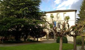 a large white building with trees in front of it at Residencia Sagrada Familia in La Seu d'Urgell