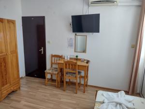 a room with a table and chairs and a tv on the wall at Къща за гости Янка in Nesebar